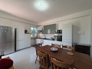 A modern kitchen with a dining area, stainless steel appliances, and a tiled floor. - La Casa dei Melograni (Marina Di Ragusa)
