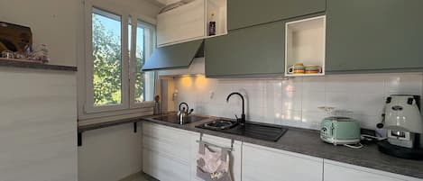 A compact kitchen with a window, a kettle, a toaster, and a coffee maker.