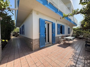 A two-story building with a balcony, a tiled patio, and outdoor furniture. - La Casa dei Melograni (Marina Di Ragusa)
