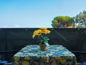 A table with a floral tablecloth and a vase of sunflowers on a balcony. - La finestra sul mare (Luni Mare)