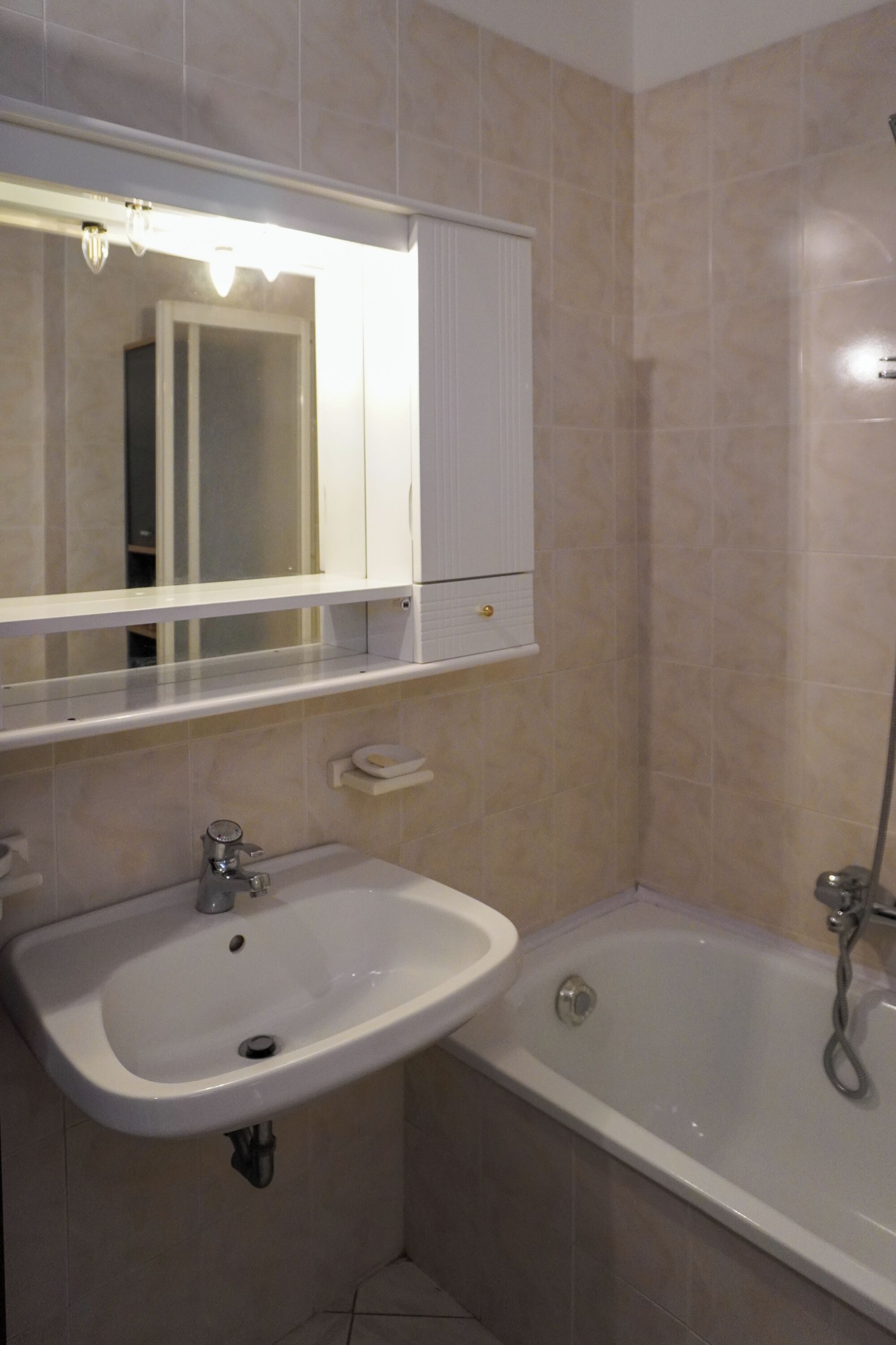 A bathroom with a sink, mirror, and bathtub.