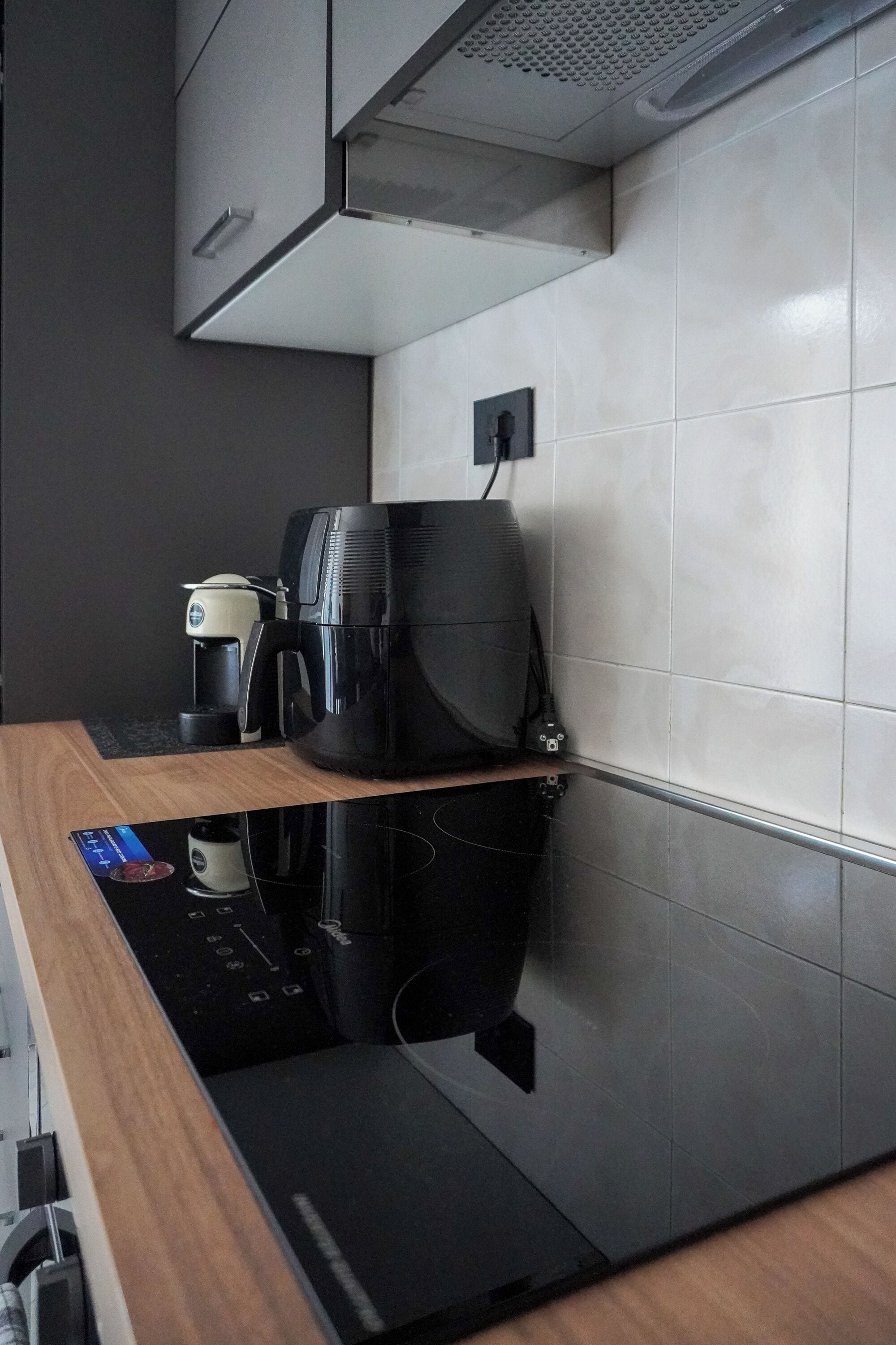 A kitchen with a black countertop, a coffee maker, and a microwave.