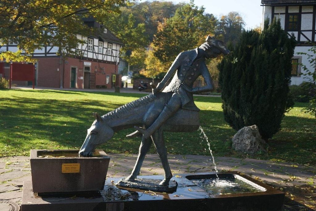 A statue of a horse drinking water, set in a stone basin with a plaque.