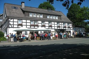 A traditional half-timbered building with a row of windows and a covered outdoor seating area. - Type B at the Gilsbach country inn (Winterberg)
