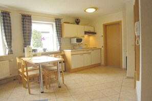 A kitchen with a dining table, chairs, cabinets, a microwave, and a window with curtains. - Type B at the Gilsbach country inn (Winterberg)