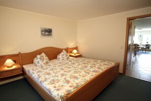 A bedroom with a wooden bed, two bedside lamps, a small bedside table, and a framed picture on the wall. - Type B at the Gilsbach country inn (Winterberg)