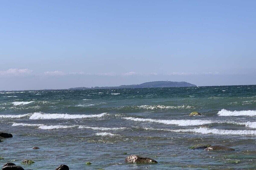 A coastal scene with waves, rocks, and a distant landmass.