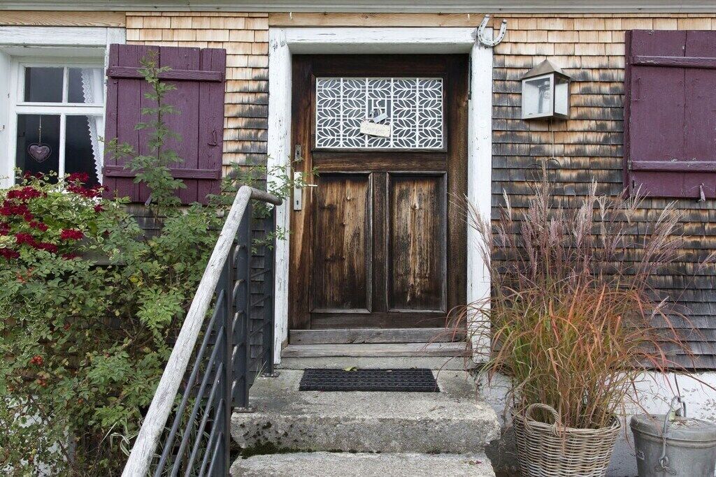 A wooden door with a decorative panel, a small porch with steps, and a metal railing.