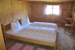 A wooden room with a bed, a window with a curtain, and a small table. - Hut "Behind" the Mountain (Hittisau)