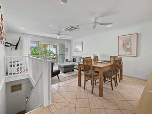 A spacious living area with a dining table, chairs, a sofa, and a ceiling fan. - Sails On Horseshoe Apartment 10 (Horseshoe Bay)