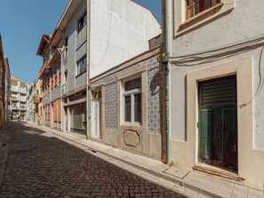 Eine Kopfsteinpflasterstraße, gesäumt von Gebäuden, einige mit Kachelfassaden, andere mit schlichten Wänden.