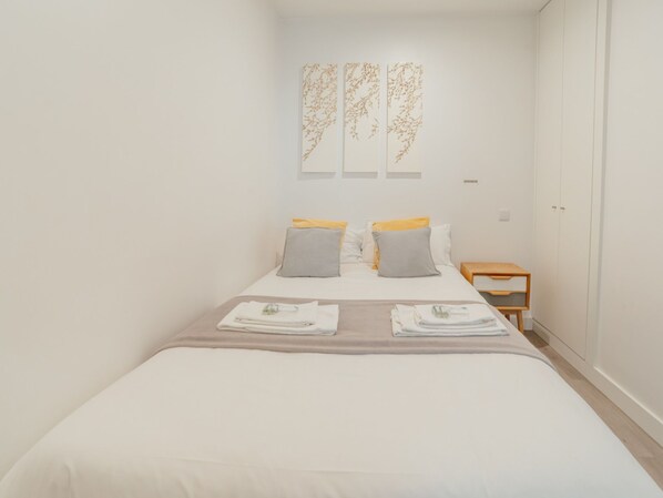 Ein Hotelzimmer mit Bett, Kissen, Nachttisch und Wandbildern.