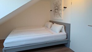 Una cama individual con cabecera en una habitación con techos inclinados.