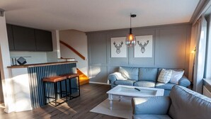 Una sala de estar moderna con un sofá, una mesa de centro y una zona de cocina con un taburete de bar.