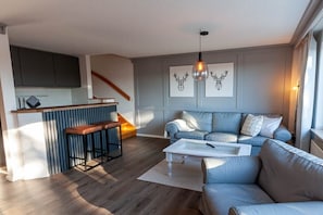 Ein modernes Wohnzimmer mit einer Couch, einem Couchtisch und einer Küchenzeile mit Barhocker.