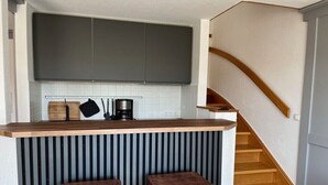Una cocina con encimera de madera, dos taburetes y una escalera.