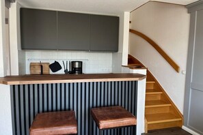 Eine Küche mit einer Holzausziehtafel, zwei Barhocker und einer Treppe.