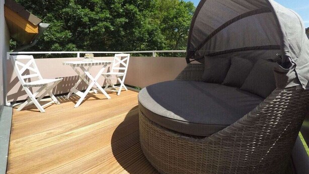 A wicker lounge chair with a canopy, a small table, and chairs on a wooden deck. - Holiday apartment with 1 bedroom (Dierhagen)