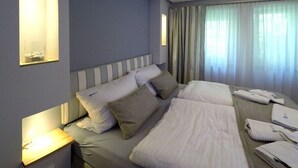 A hotel room with a large bed, bedside lamps, a window with curtains, and a wall-mounted light. - Holiday apartment with 1 bedroom (Dierhagen)