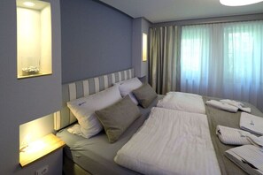 Ein Hotelzimmer mit einem großen Bett, Nachttischlampen, einem Fenster mit Vorhängen und einer Wandleuchte.