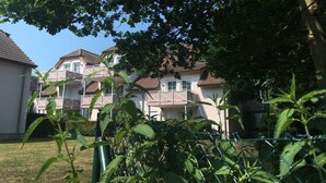 A residential building with multiple balconies, a clear sky, and a fenced garden area. - Holiday apartment with 1 bedroom (Dierhagen)