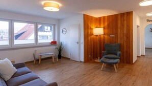Een moderne woonkamer met een houten accentmuur, een groene fauteuil en een bank.