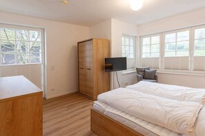 Ein Schlafzimmer mit einem Bett, einem Kleiderschrank, einem Fernseher und Fenstern.