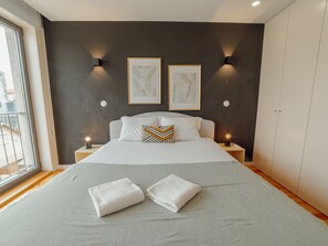 A modern bedroom with a large bed, two wall-mounted light fixtures, and two framed artworks. - Apartment  by Interhome (Porto)