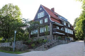 A multi-story house with a stone facade, a red-tiled roof, and a staircase leading to the entrance. - Holiday apartment with 3 bedrooms (Braunlage)