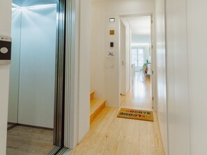 A hallway with a wooden floor, a doormat, and a door leading to a room with a bed and a window. - Apartment  by Interhome (Porto)