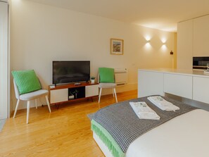 A modern hotel room with a bed, a desk with a flat-screen TV, two chairs, a small potted plant, and a wall-mounted picture. - Apartment  by Interhome (Porto)