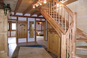 A wooden staircase with a railing, a wooden door with a handle, and a patterned rug on the floor. - Adlerhorst-Hunsrück Nature Residence (Hattgenstein)