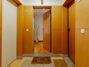 Ein Flur mit Holztüren, einem Lichtschalter und einem kleinen Teppich.