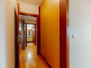 Ein Korridor mit Holzboden, der zu einem Raum mit einer großen Holztür führt.