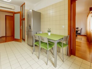 A kitchen with a dining table, chairs, a refrigerator, and a small potted plant. - DOWNTOWN DELUXE 3 by VACATIONY by Interhome (Porto)