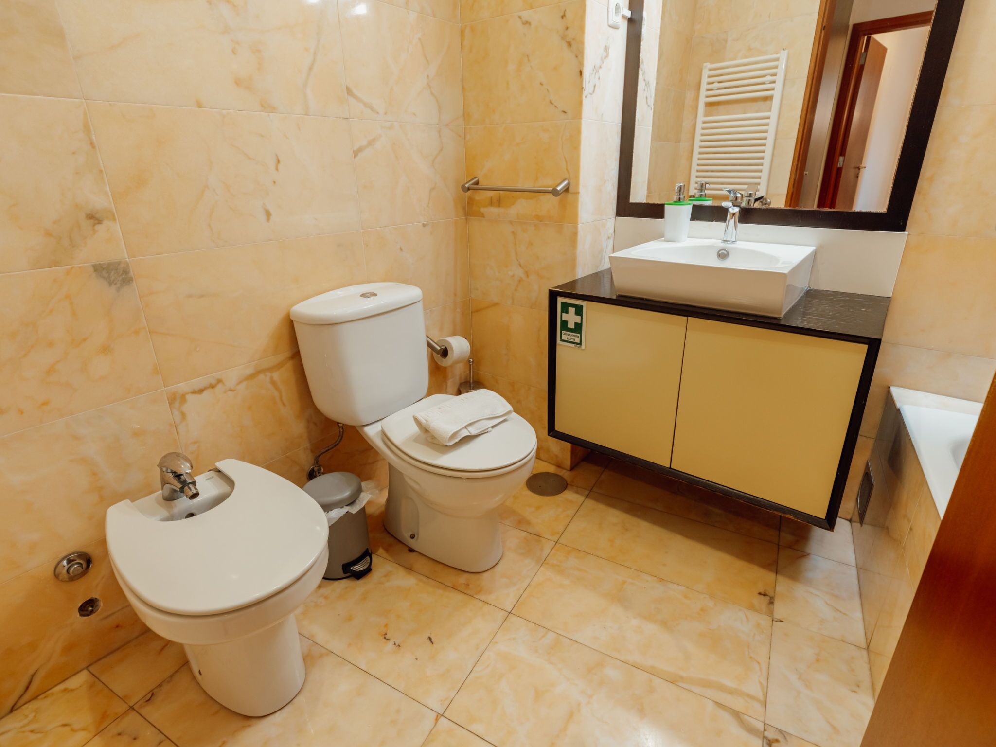 Une salle de bain avec deux toilettes, un lavabo et un miroir.