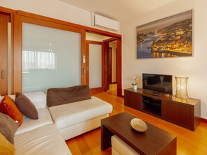 A modern living room with a sofa, TV, and a painting of a cityscape. - DOWNTOWN DELUXE 3 by VACATIONY by Interhome (Porto)