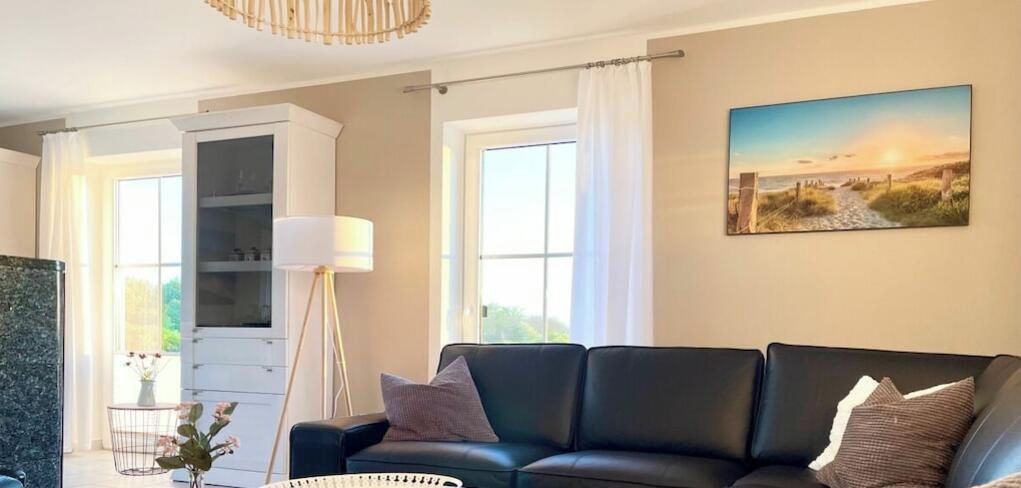 Un salon avec un canapé en cuir noir, un meuble blanc et un tableau accroché au mur.
