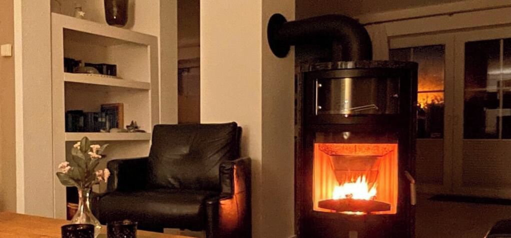 A room with a wood-burning stove, a leather armchair, and a bookshelf.