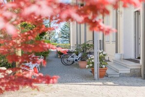 Ein gepflasterter Weg führt zu einem Gebäudeeingang, an dessen Seite ein Fahrrad abgestellt ist.