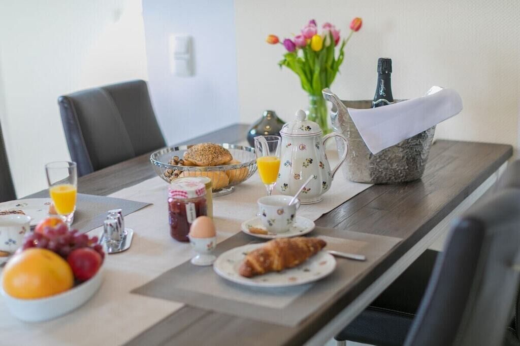 A breakfast table with croissants, fruit, juice, and a coffee pot.