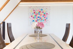 A dining area with a table, chairs, and a vase of flowers. - F2 in the house by the sea (Wenningstedt)