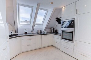 Une cuisine moderne avec des armoires blanches, un comptoir noir et un four encastré.