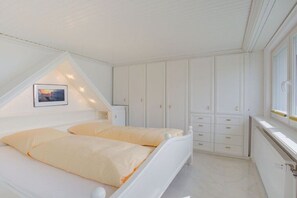 Une chambre à coucher avec un lit, une table de chevet, une armoire et une fenêtre.