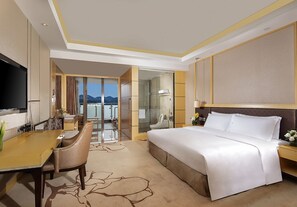A hotel room with a bed, a desk, a chair, a TV, and a view of the outdoors. - Kingworld Hotel Gui'an (Fuzhou)