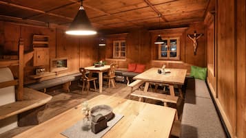 Interior acollidor d'una cabana de fusta amb taula de dinar, bancs i una llar de foc.