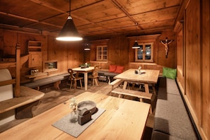 Interior acolhedor de uma cabana de madeira, com uma mesa de jantar, bancos e lareira.