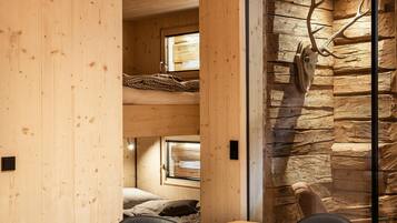 A wooden interior with a stone wall and a large antler decoration.