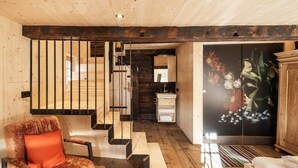 Ein Holzinnenraum mit Treppe, einer Couch, einem Schrank und einem Blumenbild.