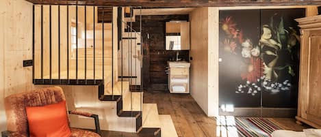 Un interior de madera con una escalera, un sofá, un armario y una obra de arte floral.